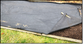 Plastic tarp covering a garden bed.